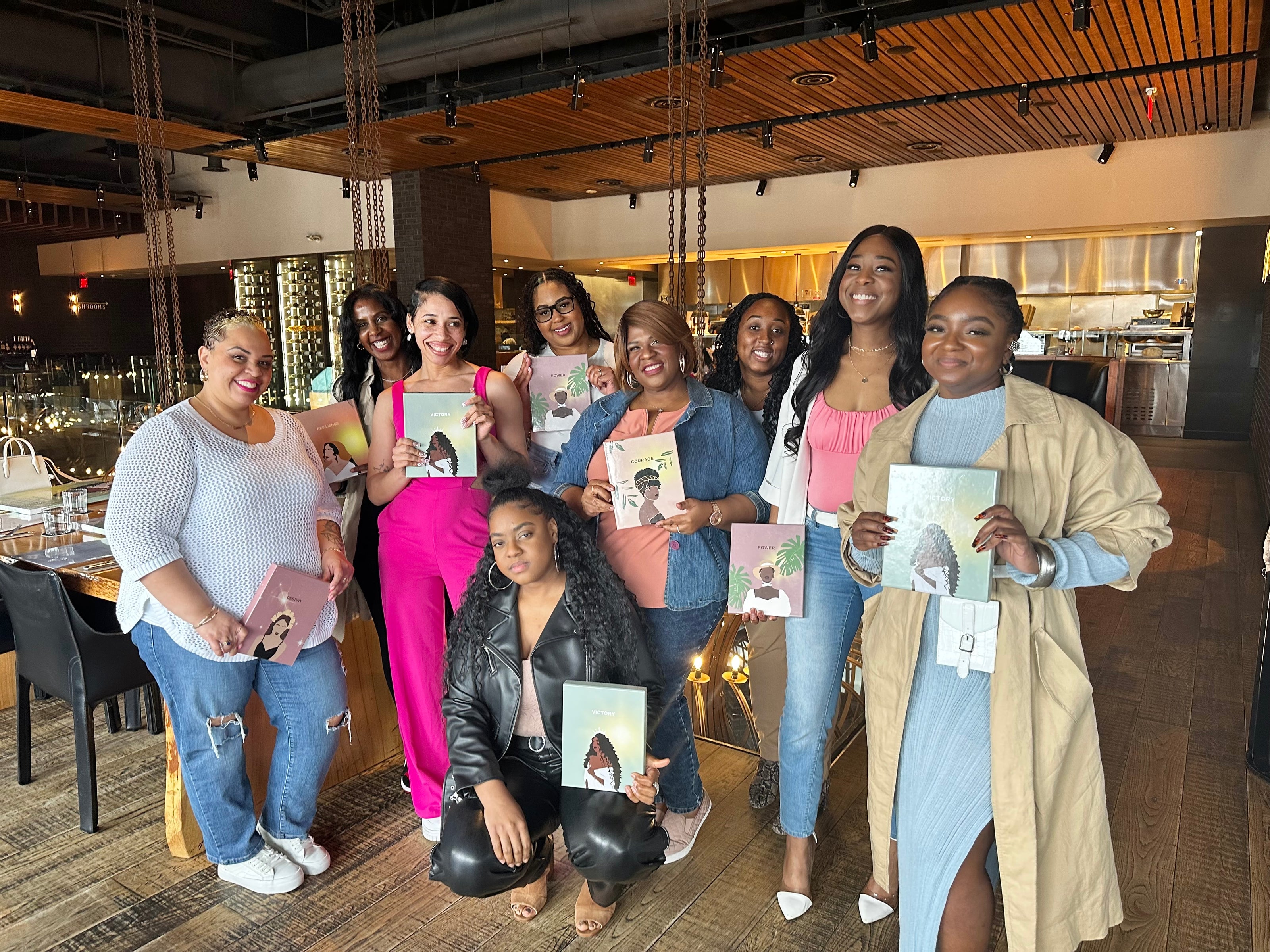 A group of smiling, diverse women holding Mindfull Mommies Journals.